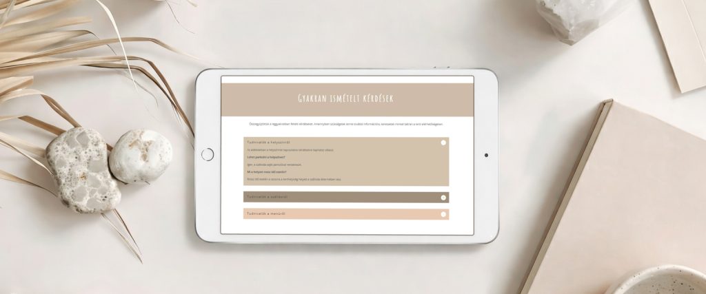 A képen egy tablet látható, rajta a gyakran ismételt kérdések szekcióval a Natural stílusú esküvői weboldalon.